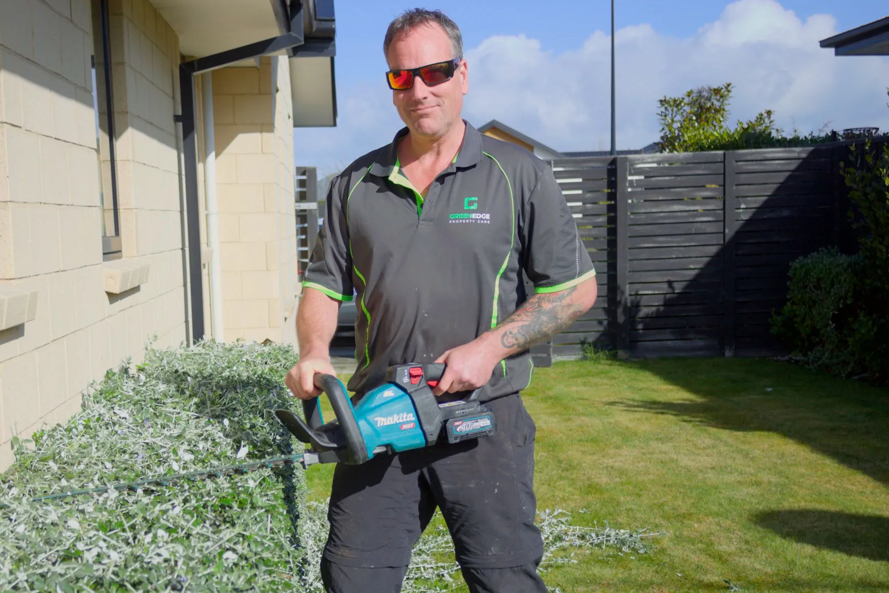 Green Edge team member using a hedge trimmer in a residential garden